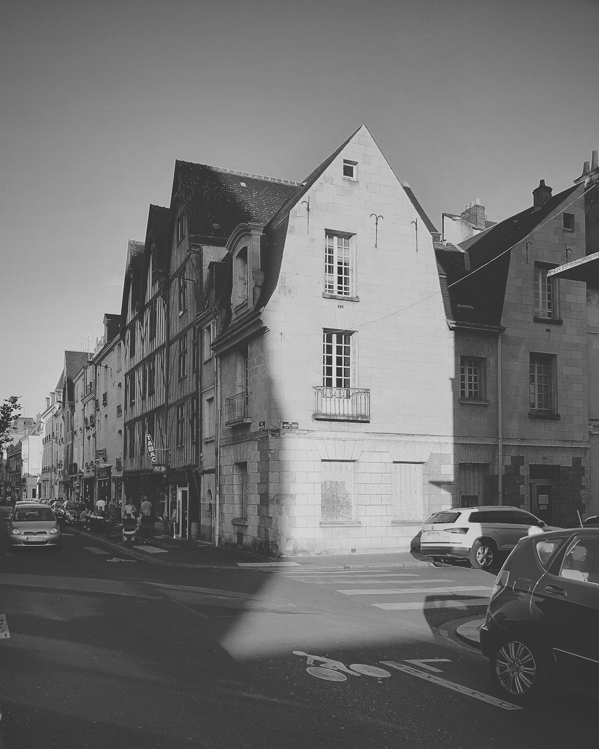 grayscale photo of cars parked beside building